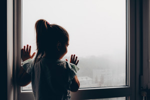 child looking out window at city with smog